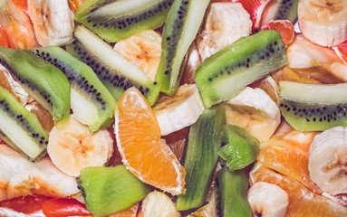 Top view of a fruit salad with bananas, oranges and kiwi