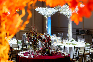 Look from behind orange autumn tree at red table