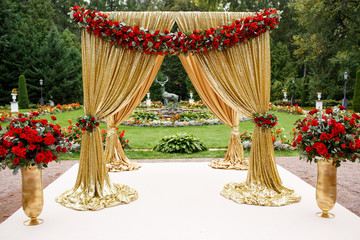 Red flower garland put on golden wedding altar