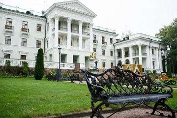 Black steel bench stands before white luxurious white house