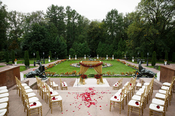 Path covered with rose petals leads between chairs to wedding al