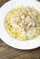 Close up of a dinner dish full of tagliatelle spaghetti with a creamy mushroom pasta sauce, on a rustic wooden table background