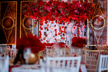 Look over white dinner tables at garland of roses hanging over d