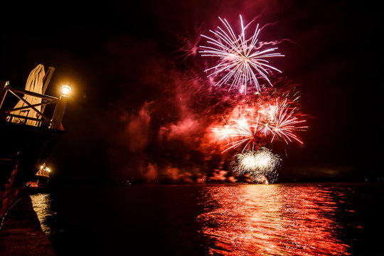 Red and violet fireworks shine over the water