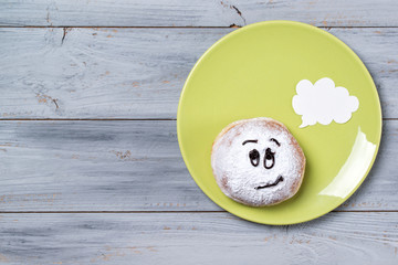 Donut with smiley face and text cloud on a plate, wooden background