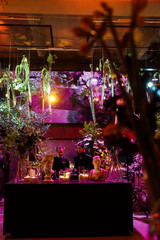 Greenery and flowers hang over bar with candles