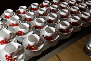 White teacups with red berries on plates
