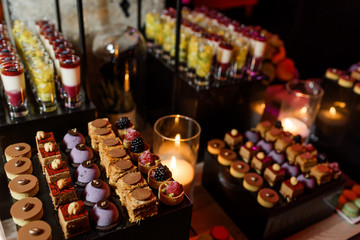 Tasty sweets and macaroons served on black boxes