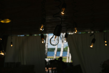 Fototapeta na wymiar Litttle yellow lamps hang in wedding pavilion