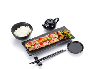 Tuna fillet fresh fried with sesame and served on a black plate isolated on white background