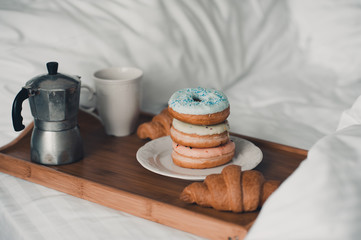 Tasty breakfast with coffee and bakery on wooden tray in bed. Good morning. Selective focus.