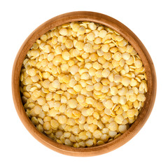 Yellow lentils in wooden bowl on white background. Seeds of Lens culinaris, edible raw pulses of the legume family. Isolated close up macro food photo from above.