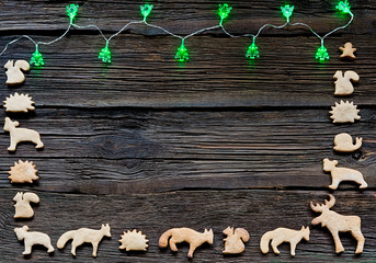 Christmas lights on a wooden background with free space. Gingerbread in the shape of animals, stars and hearts