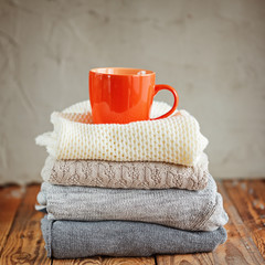 Sweaters Closeup, Stack of knitted winter clothes on wooden background.