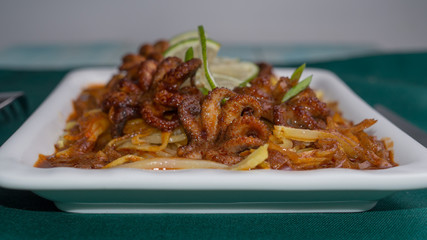 Grilled octopus with potatoes and paprika sauce on a dark green background