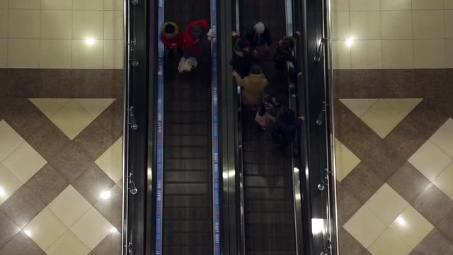 People with shopping riding the escalator in the mall
