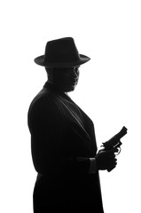 Silhouette of private detective with a gun in right hand. Agent stay side to camera and looks like...