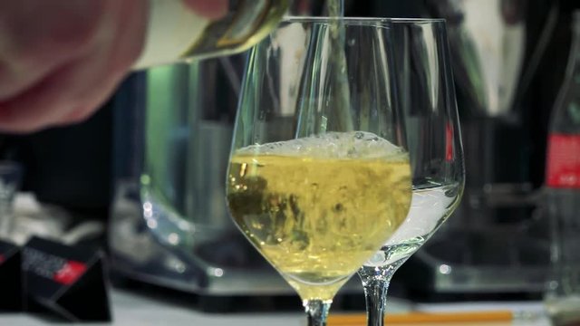 Man pour white wine to the wine glass - close up wine glass
