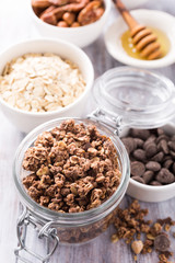 Homemade chocolate granola ingredients, nuts, oats, honey on white wooden background. Healthy brakfast concept.