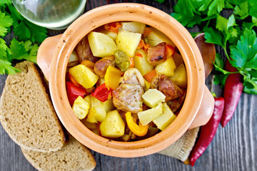 Roast meat and potatoes in clay pot on board top