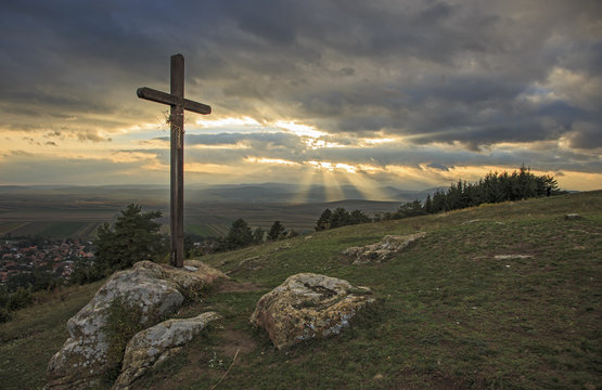 Wooden cross on hill with sunbeam