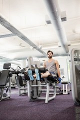 Fototapeta na wymiar Focused man using weights machine for legs