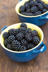 Fresh blackberry in dish on wooden texture