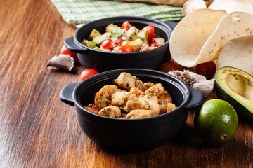 Ingredients ready for preparing chicken tacos with salsa made from avocado, tomatoes, and chilli peppers
