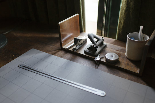 A desk in a study with a ruler, a stapler and a hole puncher.