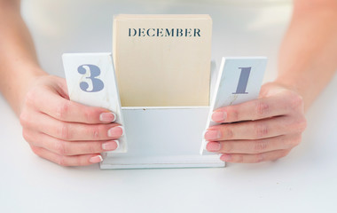 Woman hands with beautiful french manicure holding calendar open on December 31