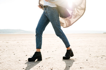 Cropped image of a casual woman walking across the beach