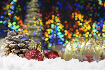 Pines, baubles and Christmas gifts on snow with shiny, glittering background 