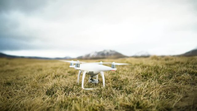 Quadcopter with camera taking off from grassy field in Iceland
