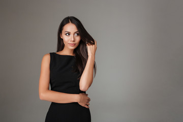 Obraz premium Portrait of smiling beautiful woman in black dress looking away