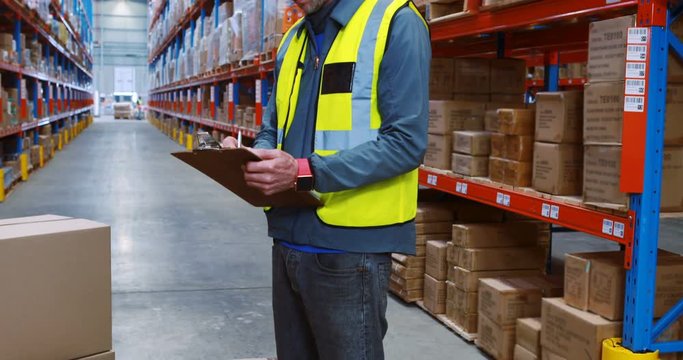 Warehouse worker writing on clipboard