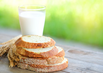 Bread cut pieces  with milk glass on wooden table,green blurred