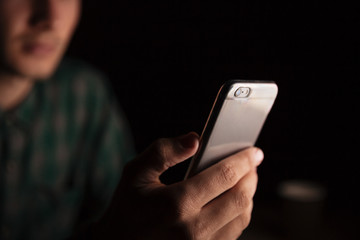 Man hand sitting and using smartphone in the evening