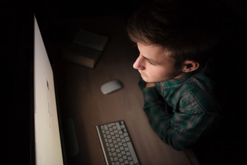 Man sitting and working with computer in the dark room