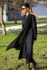 Woman in sunglasses walks in the black coat park