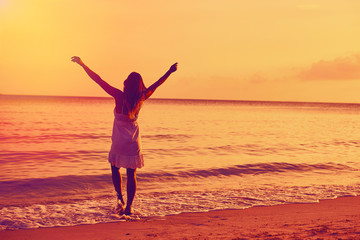 Fototapeta na wymiar Woman enjoying freedom on a ocean shore with hands raised