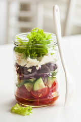 healthy greek salad in mason jar. tomato olive feta onion