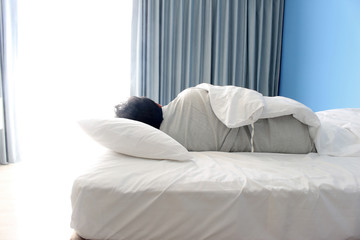 man turn back sleeping on bed in hotel bedroom