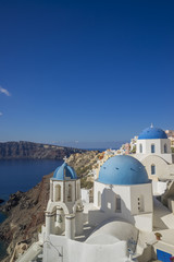 Scenic view of traditional cycladic white houses and blue domes in Oia village, Santorini island,...