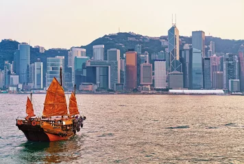 Tuinposter Junk boat at Victoria Harbor of Hong Kong at sunset © Roman Babakin