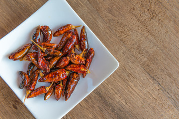 Fried Chillies with wood background, close up