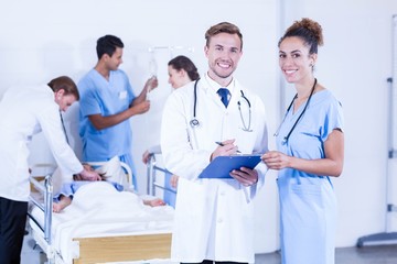 Doctors holding clipboard and smiling at camera