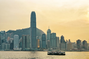 Star ferry in Victoria Harbor and HK skyline at sunset