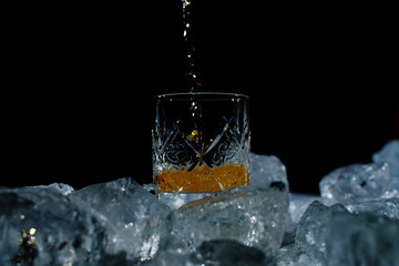 Close up photo of chunks of ice and glass of whiskey