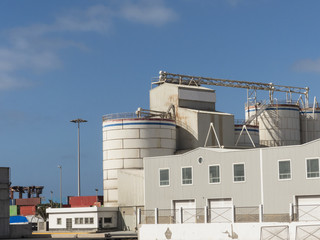 Warehouse with silos on a pier in a harbor at blue sky.
