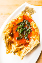 Fried sea bass fish in white plate with spicy and sweet sauce